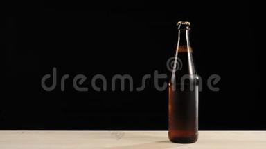 新<strong>鲜啤酒</strong>。 手拿一个棕色的瓶子和美味的工艺<strong>啤酒</strong>从木桌上黑色背景。 冷<strong>鲜啤酒</strong>